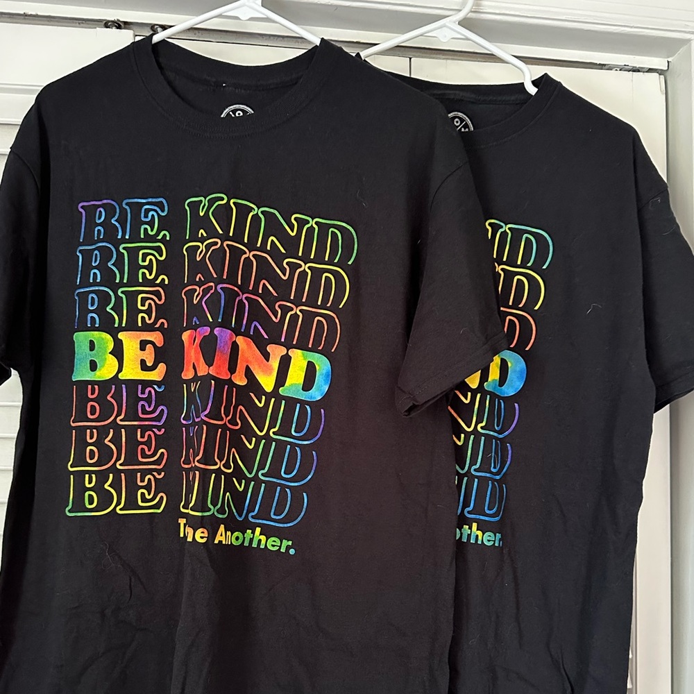 “Be Kind To One Another.” black tees with rainbow lettering